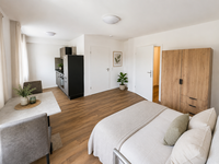 Appartement mit Einbauküche, Bett, Schrank und Tisch mit Stühlen (mit KI möbliert)